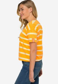 Camiseta corta de manga corta en un color naranja brillante con rayas blancas. Presenta un cuello redondo y un pequeño detalle de logo en la manga. Material de algodón suave.