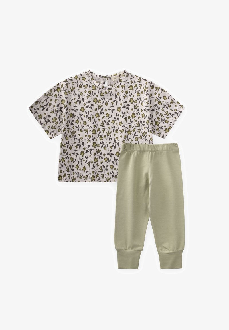 Kreklu ar īsām piedurknēm baltā krāsā ar zaļiem un pelēkiem ziedu rakstiem, apvienojot ar gaiši zaļām biksēm ar elastīgu jostu un piespraustiem potīšu galiem.