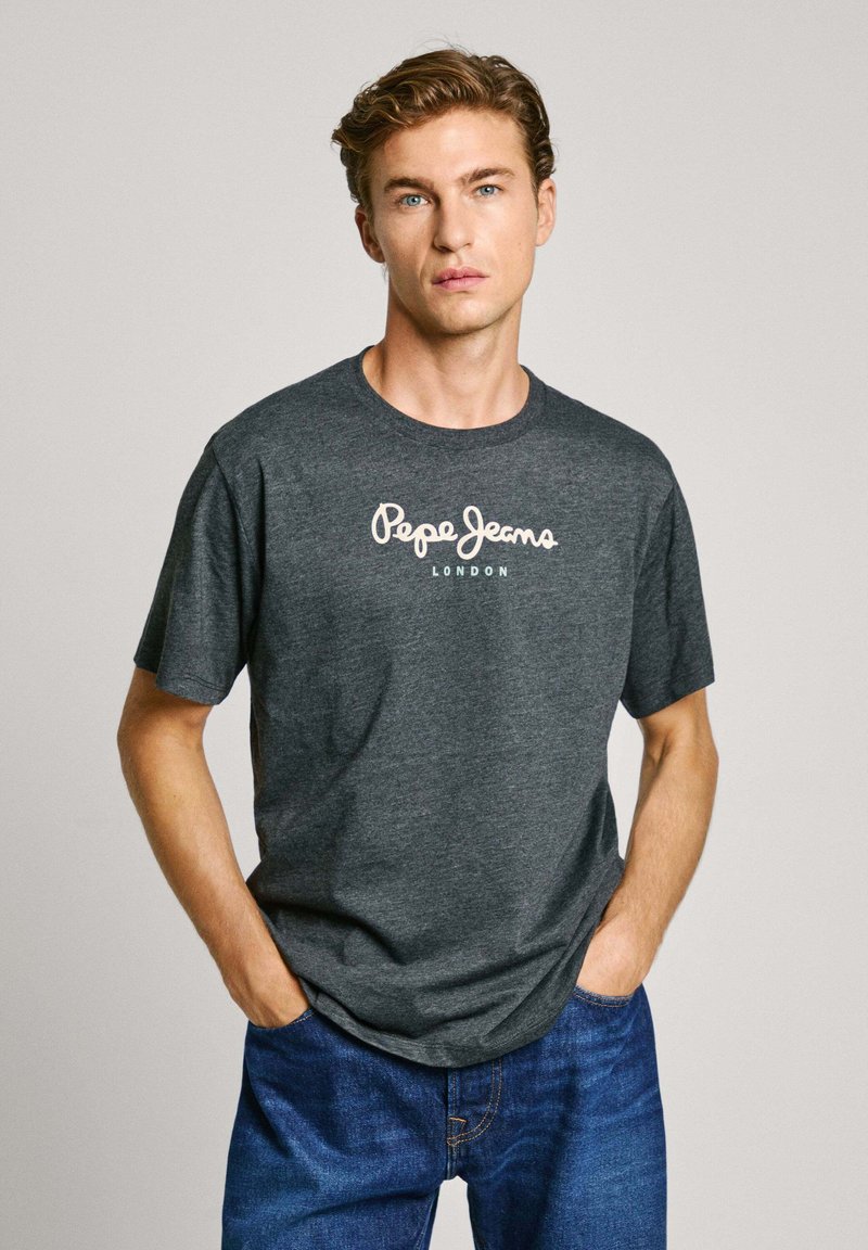 Grå bomull t-skjorte med korte ermer, rund hals og hvit "Pepe Jeans London" logo trykt på forsiden. Brukt med blå denim jeans.