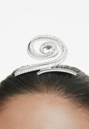 A decorative hair accessory featuring a spiral design with a large clear gem at the center and smaller stones along the edges.
