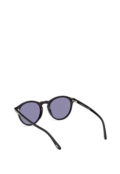 Ochelari de soare negri cu lentile rotunde, având sticlă cu nuanță violet și brațe subțiri negre. Ramele au o finisare lucioasă și o ușoară formă de ochi de pisică.