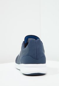 Námořnické modré sportovní boty s síťovaným svrškem a semišovými akcenty, s bílou mezipodešví a zaobleným designem paty. Zobrazeno ze zadní strany.