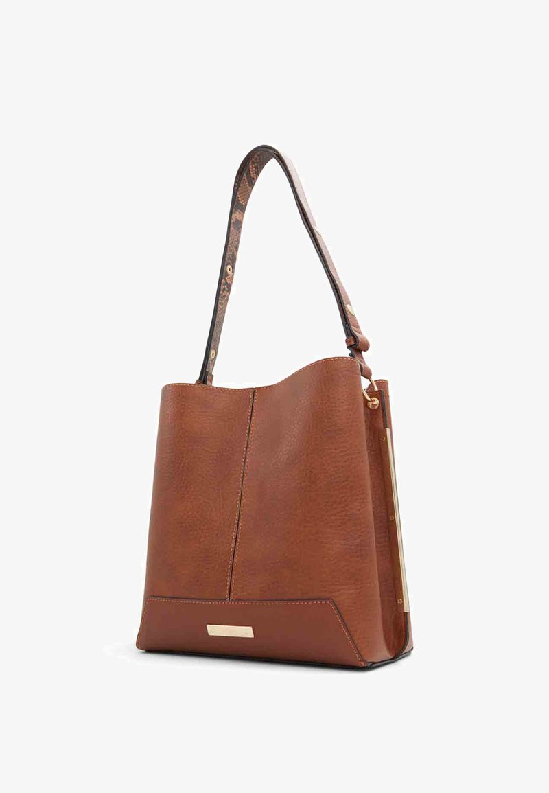 Sac fourre-tout en cuir marron avec surface texturée et bandoulière réglable à motif, avec une petite plaque nominative dorée sur le devant.