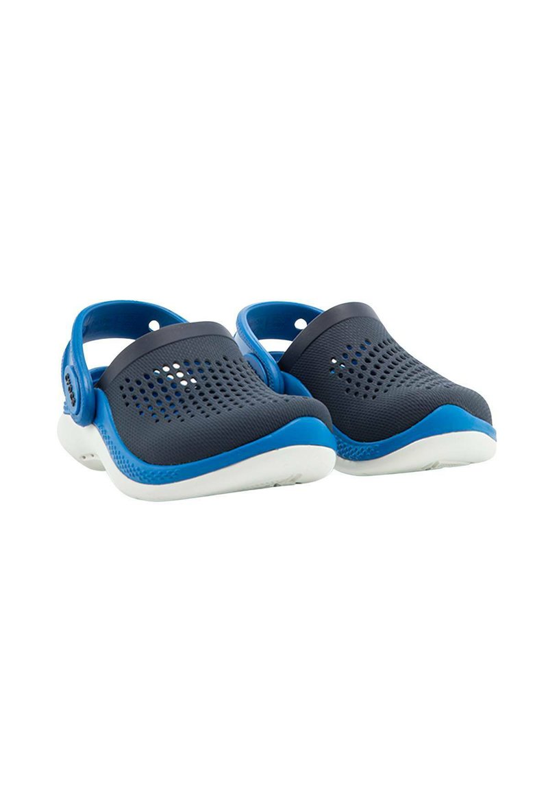 Zuecos azules y negros hechos de un material flexible, con orificios de ventilación, una correa trasera y una suela blanca.