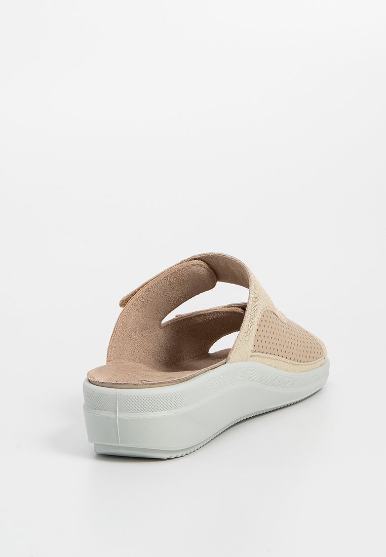 Sandal alba aperta beige con tomaia testurizzata e design perforato. Presenta una soletta imbottita e una suola a piattaforma bianca.