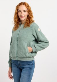 Fleece bomberjack in zacht mintgroen met een ritssluiting aan de voorkant, geribde manchetten en een patch op de mouw. Voorzien van zijzakken en een gestructureerde stof.