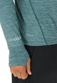 Groen sportshirt met lange mouwen, gemaakt van sneldrogend materiaal, met een gestructureerd oppervlak, duimopeningen en reflecterende accenten op de mouw.