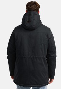 Sort udendørsjakke med hætte, der har et tekstureret stof, en indsnævret taljedesign og en justerbar rygrem.