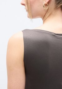 Haut sans manches gris en coton doux, avec un col arrondi et une silhouette cintrée, présentant une texture lisse et des coutures minimales.