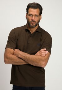 Polo shirt marron avec col et patte de boutonnage à trois boutons. Présente des manches courtes, un tissu légèrement texturé et un petit logo imprimé sur la poitrine.