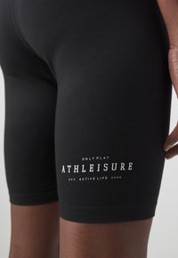 Fekete sportnadrág rugalmas anyagból, fehér logóval, ami így szól: "ONLY PLAY ATHLEISURE EST. ACTIVE LIFE 2006."