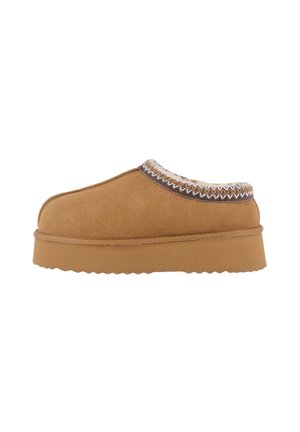 Zapato de ante en color marrón claro, tipo mocasín, con un forro texturizado en color crema y un acento de costura decorativa a lo largo del collar. Suela de goma gruesa con un borde ondulado.
