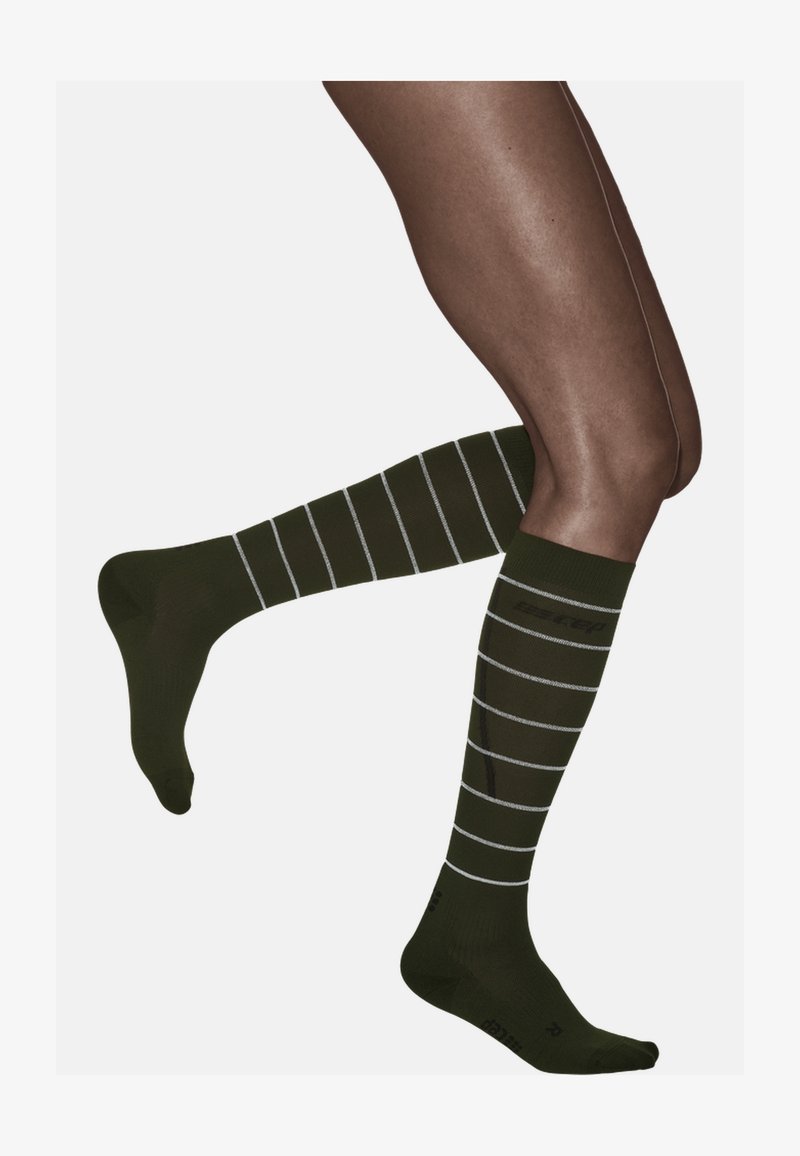 Dunkelgrüne, knielange Socken mit weißen horizontalen Streifen, die eine weiche Textur und eine enge Passform aufweisen, ideal für Komfort und Unterstützung.