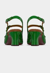 Sandales en cuir verni vert avec un talon arrondi, deux sangles de cheville réglables et une texture lisse, dotées d'une semelle intérieure marron et d'une finition brillante.