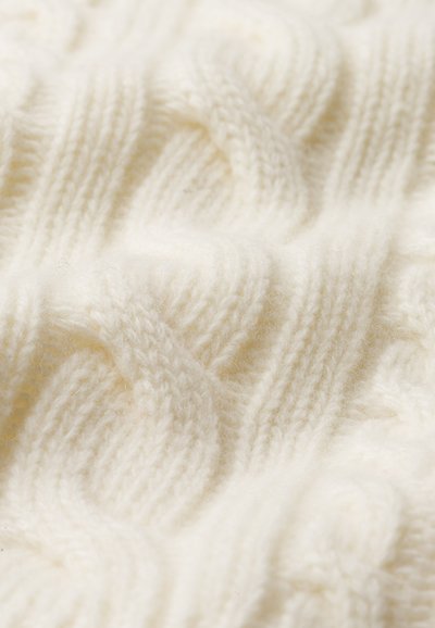 Kreminės spalvos megzta medžiaga su tekstūruotu kabelio raštu, turinti lygiagrečius varpinius raštus ir švelnų, pūkuotą išvaizdą.