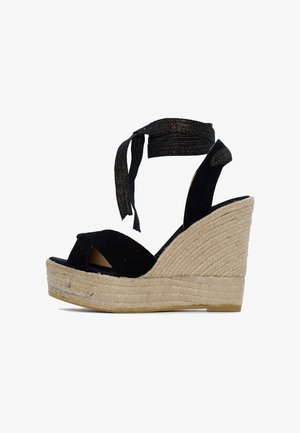Sandali con zeppa in suede nera con suola in juta intrecciata, dotati di una ampia fascia sulla punta e lacci alla caviglia per una vestibilità regolabile.