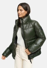 Groene pufferjack met een hoge kraag, glanzende textuur, ritssluiting aan de voorkant en zijzakken. Opvallende paneelstikseldetails op de mouwen.