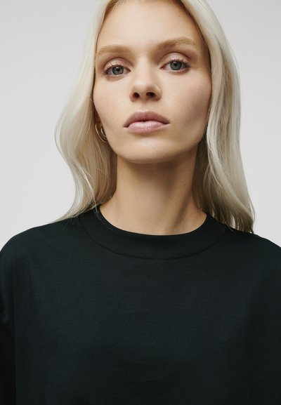 Black t-shirt with a round neckline and short sleeves, displayed against a neutral background. Smooth texture, minimalistic design.