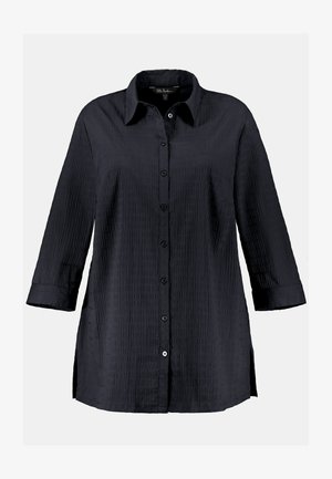 Černá košile na knoflíky vyrobená z texturované tkaniny, s límečkem, dlouhými rukávy a bočními rozparky pro snadnější pohyb.