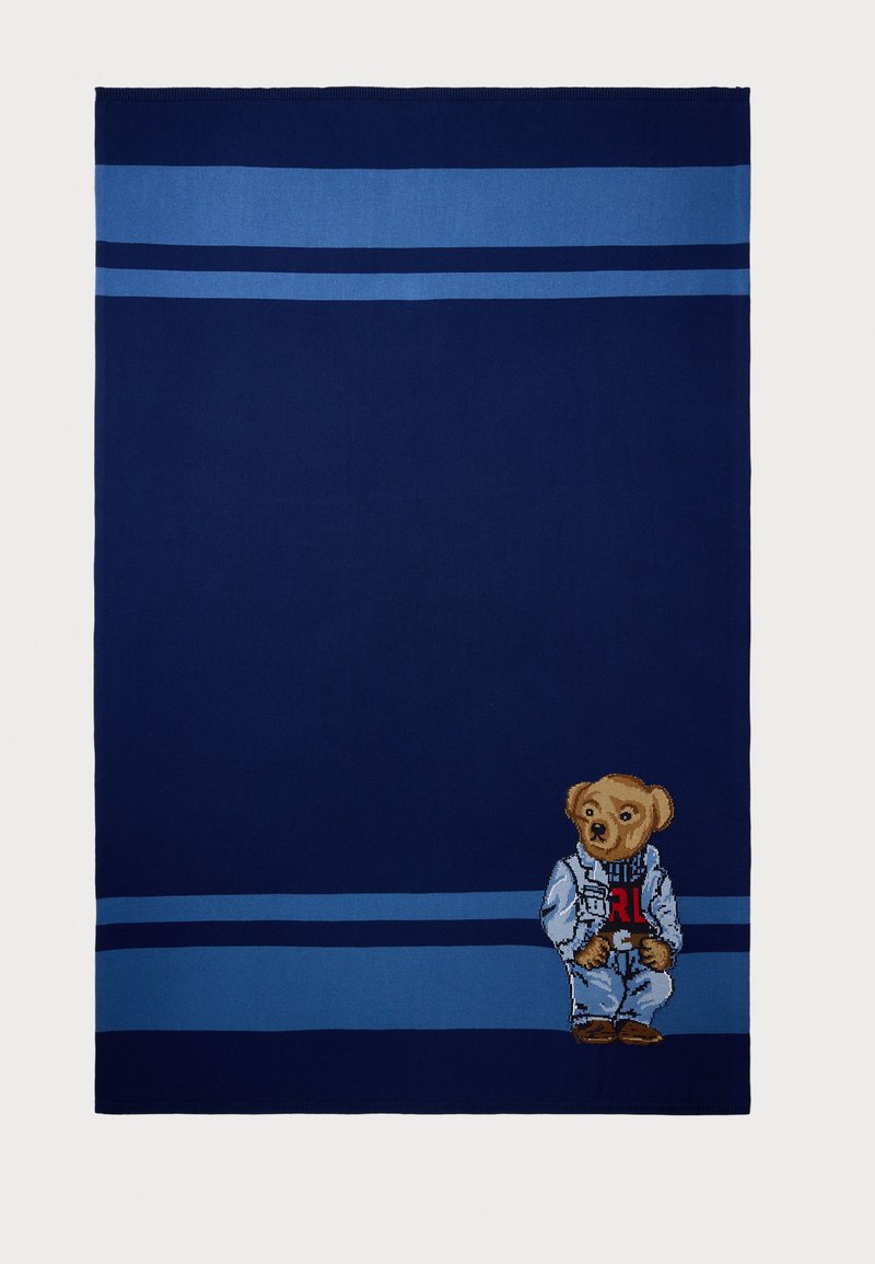 Navy blue blanket with horizontal blue stripes. Features an embroidered bear in a denim jacket, standing on the lower left corner.