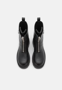 Paire de bottines en cuir noir avec semelles épaisses et fermetures éclair argentées à l'avant, vues de dessus sur fond blanc.