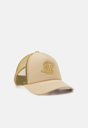 Casquette de baseball beige avec dos en mesh doré et initiales entrelacées brodées sur le panneau avant, positionnée inclinée vers la droite sur fond blanc.