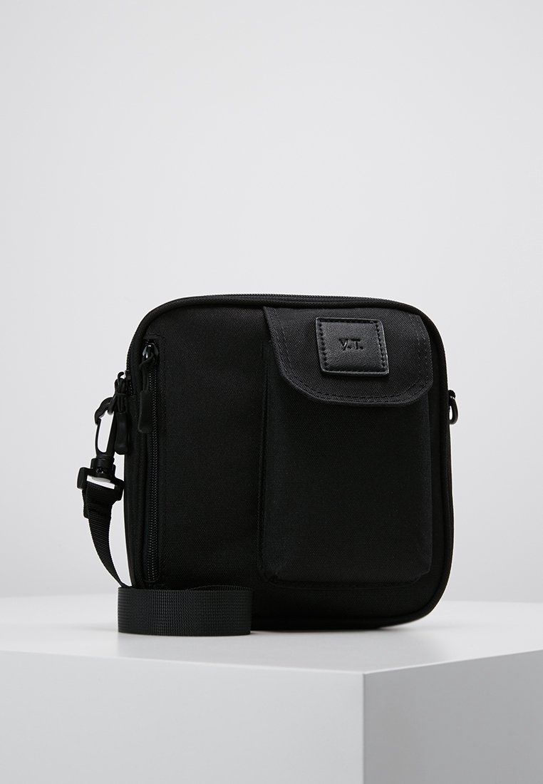 Sort nylon crossbody taske med en struktureret overflade, lynlås lukning, frontlomme med klap, justerbar rem og mærke på fronten.