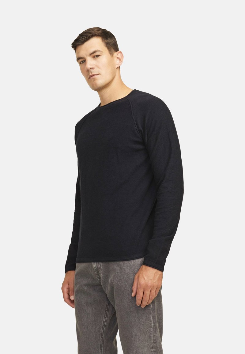 Camisa de manga larga de cuello redondo en color navy, hecha de tela texturizada. Silueta ajustada con puños acanalados y un acabado suave. Combinada con jeans grises.