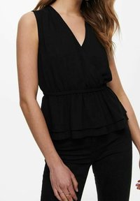 Top nero senza maniche con scollatura a V, vita elasticizzata, design a peplum a strati e morbida texture del tessuto, indossato con pantaloni neri.