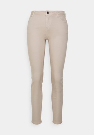 Pantalon skinny beige taille haute avec poches avant, passants pour ceinture, fermeture à bouton et ourlet à la cheville sur fond blanc.
