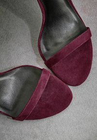 Sandales à enfiler en suede bourgogne avec une semelle intérieure noire lisse et une large sangle supérieure. Dotées d'un bout arrondi et d'un design minimaliste.