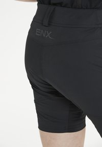 Svarta atletiska shorts med en åtsittande design, som har en slät textur, elastisk midja och "ENX"-logotypen på baksidan.