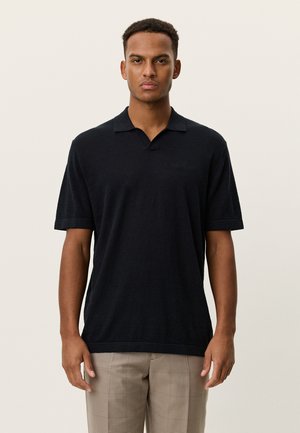 Polo nera a maniche corte con scollo a V e logo ricamato sottile sul petto, realizzata in tessuto strutturato.
