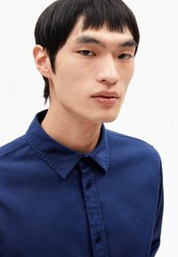 Donkerblauw overhemd met knopen, gemaakt van zachte stof, met een puntkraag en een klein geborduurd logo op de linkerborst.