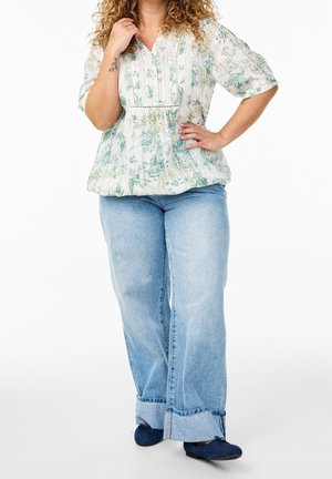 Floral-patterned blouse with a smocked waist, featuring a v-neck and short sleeves. Paired with light blue wide-leg jeans.