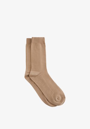 Calzini beige con motivo lavorato a maglia e bordi a coste. Il materiale appare morbido ed elastico, rifinito con una punta arrotondata.