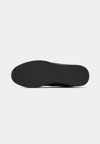 Black sneaker sole with textured grip pattern, rounded shape, and subtle logo detail. Material appears rubberized for durability.