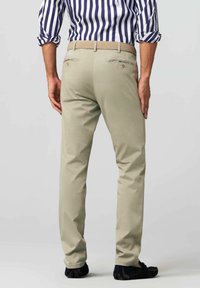 Tan chinos with a slim fit, featuring back pockets with flaps, a woven beige belt, and subtle stitching accents.