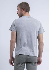 T-shirt gris à manches courtes en tissu doux, avec un col rond, une coupe décontractée et un ourlet droit à l'arrière.