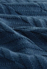 Ciemnoniebieska dzianina z fakturowanym wzorem zygzaka, prezentująca miękkie włókna i pofalowany układ dla głębi i wymiaru.