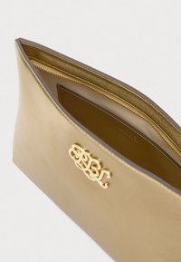 Arany színű bőr clutchnak sima felülete van, elülső részén arany logóval és kontrasztos belső térrel ellátott zipzárral.