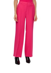 Heldere roze wijde broek met een gladde stof, voorzien van een hoge taille en voorplooien. Gemaakt in combinatie met zwarte hoge laarzen voor contrast.