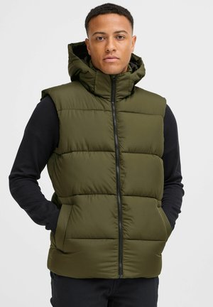Green padded vest with a hood, featuring a front zipper, and side pockets. Worn over a black long-sleeve shirt. Smooth texture.