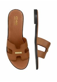 Brązowe skórzane klapki z wyciętym wzorem i złotym logo. Czarna gumowa podeszwa z teksturowanym uchwytem. Płaski, otwarty styl z odkrytymi palcami.