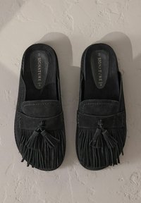 Chaussures noires en daim à enfiler avec un design à franges et un gland décoratif à l'avant. Intérieur uni avec des détails de couture.