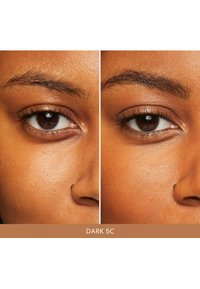 Gros plan de deux yeux marron avec des cils foncés, une texture de peau lisse et des sourcils bien définis ; étiqueté "DARK 5C" en bas.