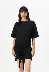 Black short-sleeve dress with a knotted front detail. Made of soft fabric, featuring a round neckline and small logo accent near the neck.