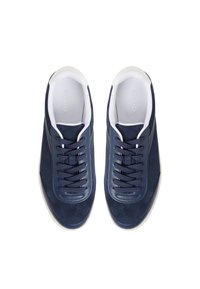 Zapatillas de ante azul marino con suelas de goma blanca, que cuentan con punta redonda, diseño de cordones y una sutil marca en el área de la lengüeta.
