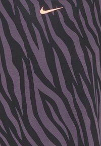 Haut Nike présentant un motif rayé zèbre noir et violet, fabriqué en tissu doux, avec un petit logo swoosh rose en haut à gauche.