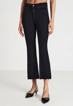 Jean noir évasé en denim, avec une taille haute, un ourlet brut et une silhouette ajustée qui s'évase au niveau de la cheville.